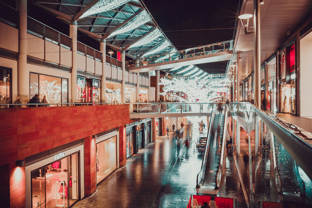 Mostly empty and dimly lit shopping centre with Christmas decorations.